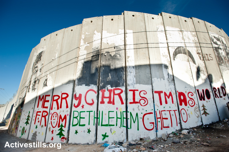 A photo from the separation wall around Bethlehem that shows red and green graffiti reading "Merry Christmas world from Bethlehem ghetto"